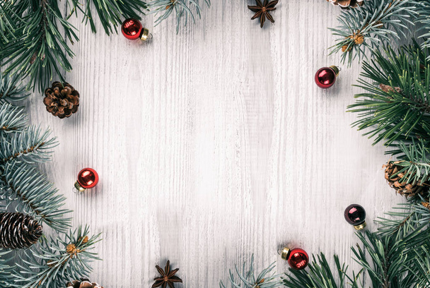 Creatieve badrand van Kerstmis fir takken op witte houten achtergrond met rode decoratie, dennenappels. Kerstmis en Nieuwjaar thema. Plat lag, top uitzicht - Foto, afbeelding