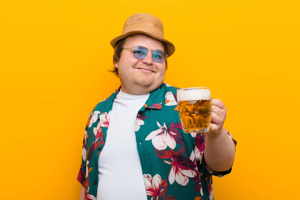 young big size man with a pint of beer against flat wall - Foto, imagen