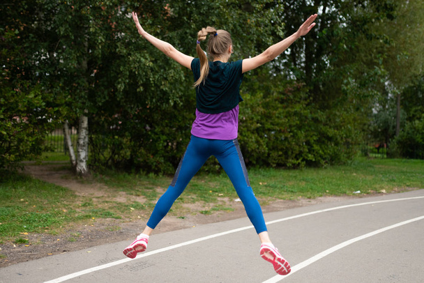Athletic girl doing stretching on a street treadmill. - Zdjęcie, obraz