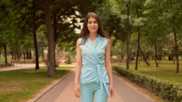 slim businesswoman in blue elegant suit walks on pedestrian zone looking camera - Materiał filmowy, wideo