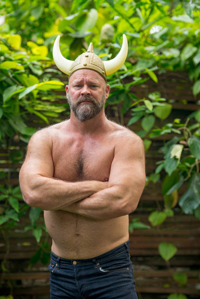 Shirtless man with a viking horned hat posing shirtless outdoors - Фото, зображення