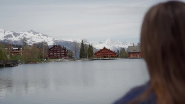 Vrouw genieten van een prachtig uitzicht over het meer en de bergen en ontspannen op zonnige lente dag. Achteraanzicht. Focus overgang - Video