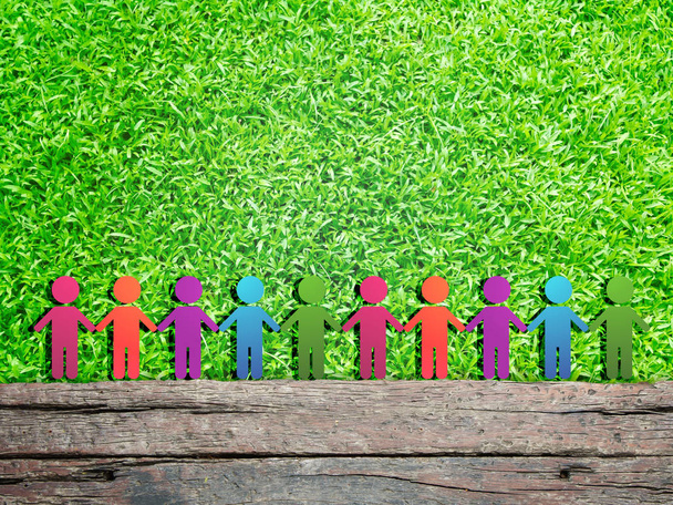 Ecologie concept: groep van kleurrijke kinderen figuur pictogram staande op houten hout en groene gras weide veld. Zij houden handen bij elkaar. - Foto, afbeelding