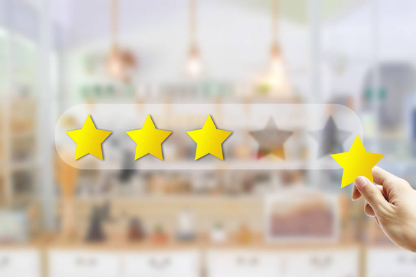 Koncepcja Opinie klientów: ręczne trzymanie i dając żółtą gwiazdę dla najlepszego rankingu usług z zamazany widok z przodu kawiarni restauracja lub kawiarnia w hotelu. - Zdjęcie, obraz