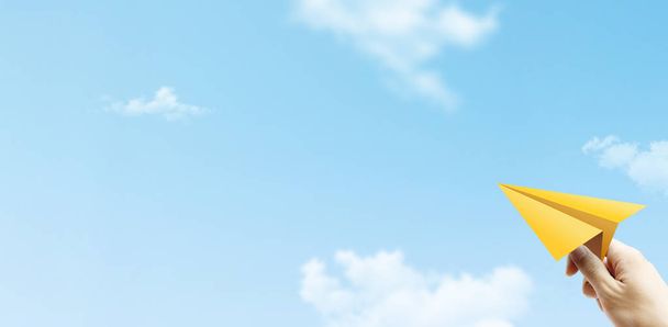 Freedom Concept : Main tenant un avion en papier jaune et jetant au ciel bleu
. - Photo, image