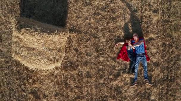 Vista superior de papá e hijo superhéroes acostados en el campo
 - Metraje, vídeo