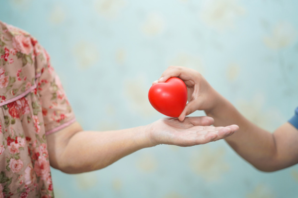 Asijské děti mladej podržte dotykový a dát červené srdce silné zdraví stará matka lady ruce s láskou, šťastný, péči, podporovat a empatie - Fotografie, Obrázek
