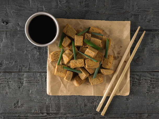 Grilled tofu cheese on paper and soy sauce on wooden table. - Photo, Image