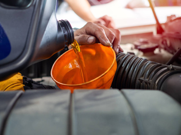Mechanic hand pouring fresh  engine oil through orange funnel in - Fotoğraf, Görsel