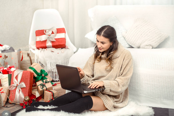 Beautiful woman with computer and Christmas gifts. - Фото, зображення