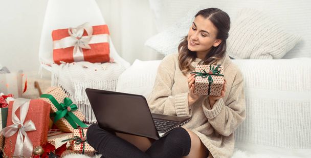 Όμορφη γυναίκα με τον υπολογιστή και τα Χριστουγεννιάτικα δώρα. - Φωτογραφία, εικόνα