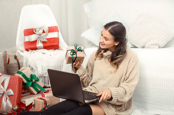 Beautiful woman with computer and Christmas gifts. - Фото, изображение