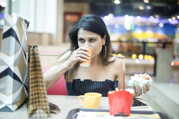Woman having food and drink after shopping at mall - 写真・画像