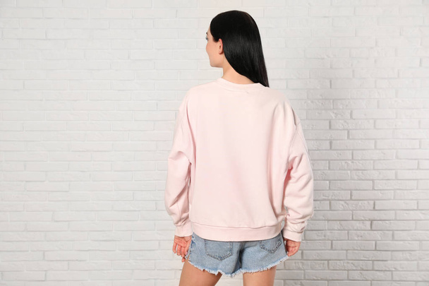Young woman in sweater at brick wall. Mock up for design - Foto, imagen