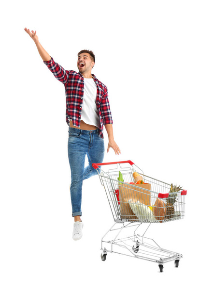 Young man with full shopping cart on white background - Foto, Imagen