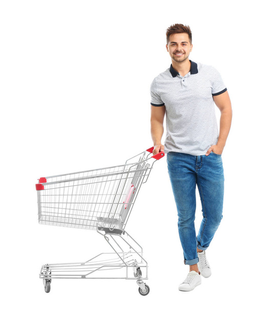 Young man with empty shopping cart on white background - Foto, Imagem