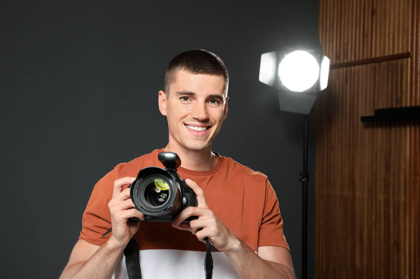 Professional photographer with modern camera in studio - Photo, image