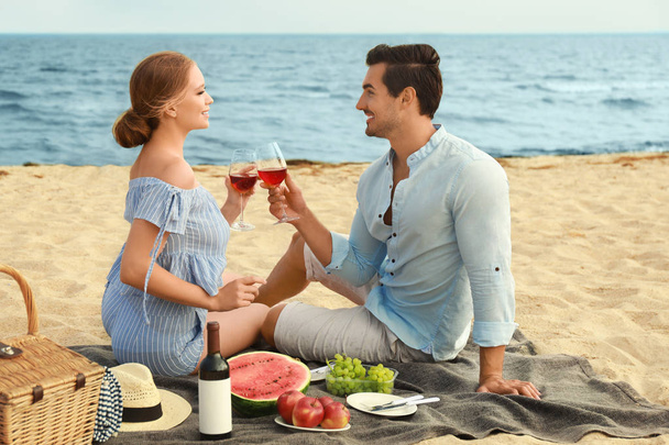 Beautiful young couple having picnic at sea beach - Fotoğraf, Görsel