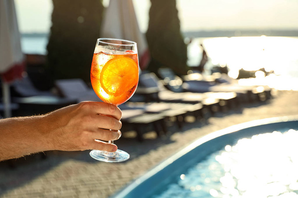 Uomo con bicchiere di fresco cocktail estivo vicino alla piscina all'aperto, primo piano. Spazio per testo
 - Foto, immagini