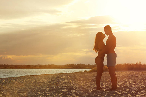 Young woman in bikini spending time with her boyfriend on beach. Lovely couple - 写真・画像