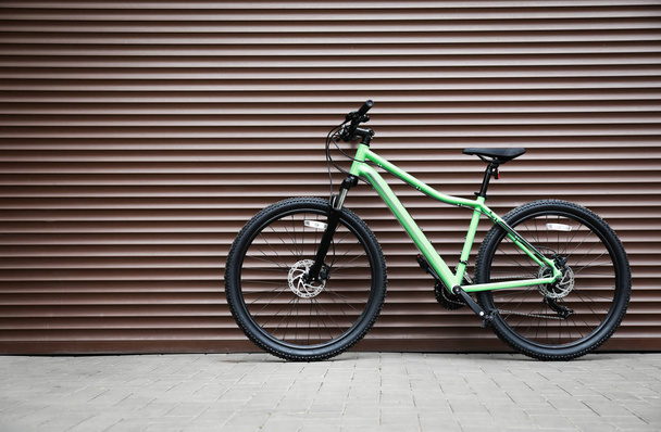 Nuova bicicletta a colori moderna vicino alla parete marrone all'aperto
 - Foto, immagini