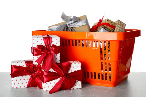 Shopping basket full of gift boxes on light grey marble table against white background - Photo, Image