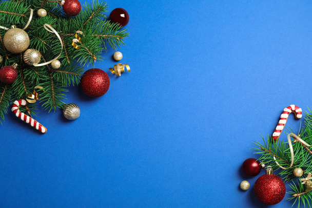Fir tree branches with Christmas decoration on blue background, flat lay. Space for text - Fotó, kép