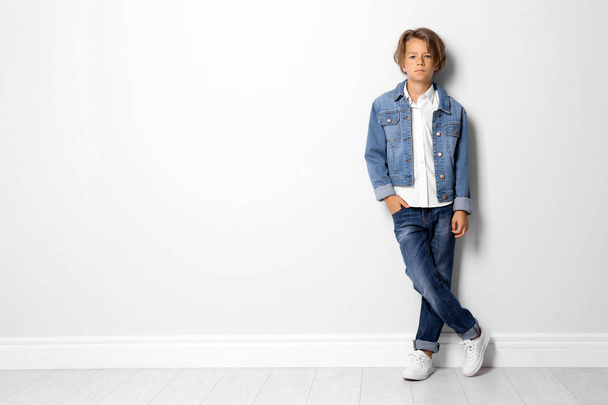 Cute little boy in casual outfit near white wall. Space for text - Zdjęcie, obraz