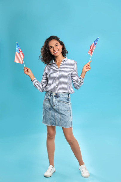 happy young woman with American flags on blue background - Фото, изображение