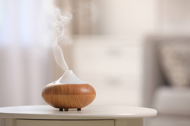 Modern essential oil diffuser on table indoors. Space for text - 写真・画像