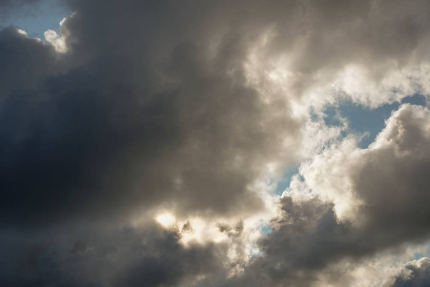 El sol y las nubes en el cielo azul. Clima nublado con cúmulos, nubes oscuras. Día de otoño. Un fuerte viento sopla, la presión es baja, el umbral de la lluvia
. - Foto, Imagen