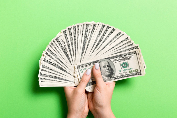 Ventilateur de billets de cent dollars à la main féminine sur fond coloré. Concept d'investissement
 - Photo, image