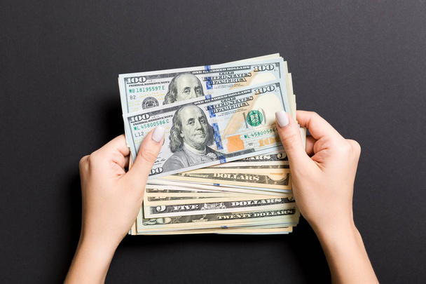 Vista dall'alto di diverse banconote in dollari in mani femminili su sfondo colorato. Concetto economico e finanziario
 - Foto, immagini