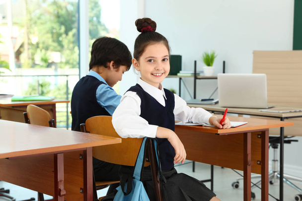 Girl wearing new school uniform in classroom - Foto, Imagen