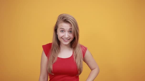 izole turuncu arka plan üzerinde kırmızı t-shirt genç sarışın kız duygularını gösterir - Video, Çekim