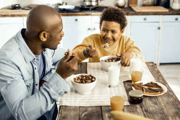 Radostný afroamerický otec se synem pojídáním zdravého jídla a mluvení o svátcích. - Fotografie, Obrázek