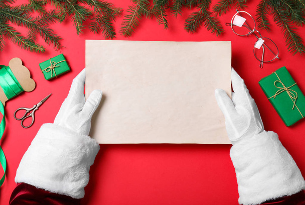 Santa Claus holding empty paper on red background, top view. Space for text - Foto, imagen