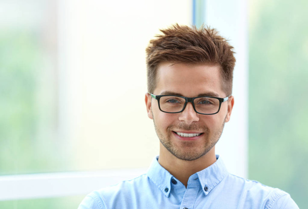 Portrait of handsome young man with glasses near window - Foto, imagen