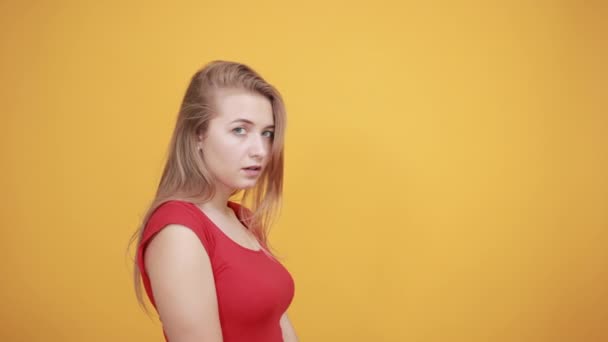 young blonde girl in red t-shirt over isolated orange background shows emotions - Video