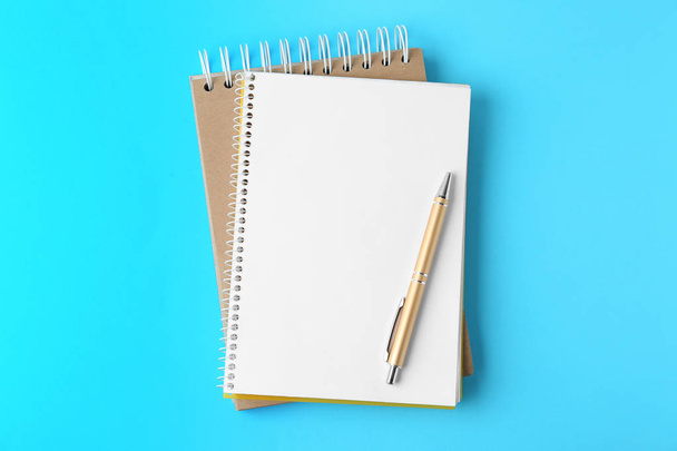 Notebooks and pen on light blue background, top view - Foto, imagen