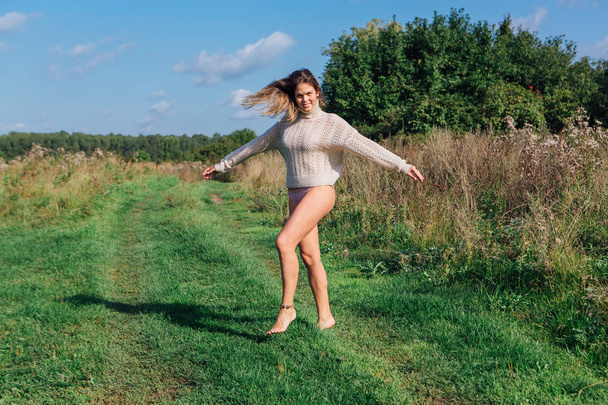 Happy young beautiful woman jumping with bare foot in a green field - Foto, Bild