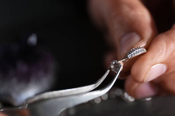 Male jeweler examining diamond ring in workshop, closeup view - Фото, изображение