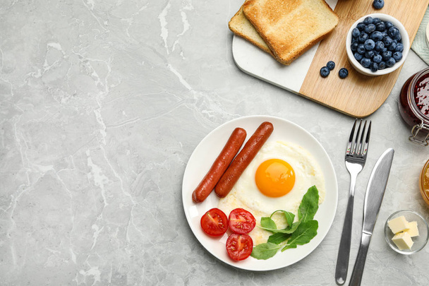 Tasty breakfast with fried egg on light grey marble table, flat lay. Space for text - Foto, Bild