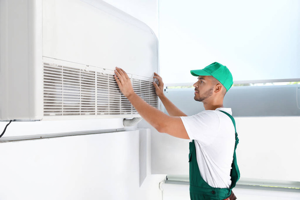 Professional technician maintaining modern air conditioner indoors - Fotó, kép