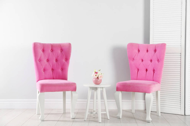 Stylish pink chairs and table near white wall in room - Foto, afbeelding