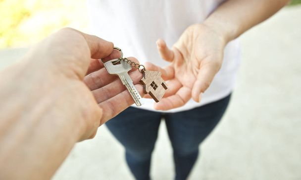 Mann gibt Metallschlüssel von Tür mit Holzschmuck in Form  - Foto, Bild