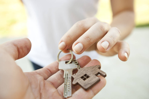 Homem dando a chave de metal da porta com bugiganga de madeira em forma de casa para a mulher
 - Foto, Imagem