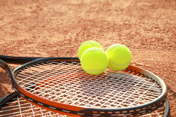 Tennispallot ja mailat kentällä
 - Valokuva, kuva