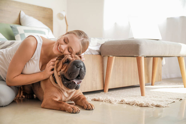 Happy woman with cute dog in bedroom - Photo, Image