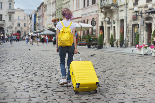 Traveler girl walking with backpack and yellow suitcase - Foto, Bild